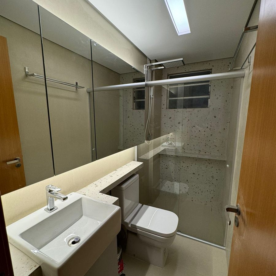 Banheiro em granilite com box de vidro e iluminação embutida