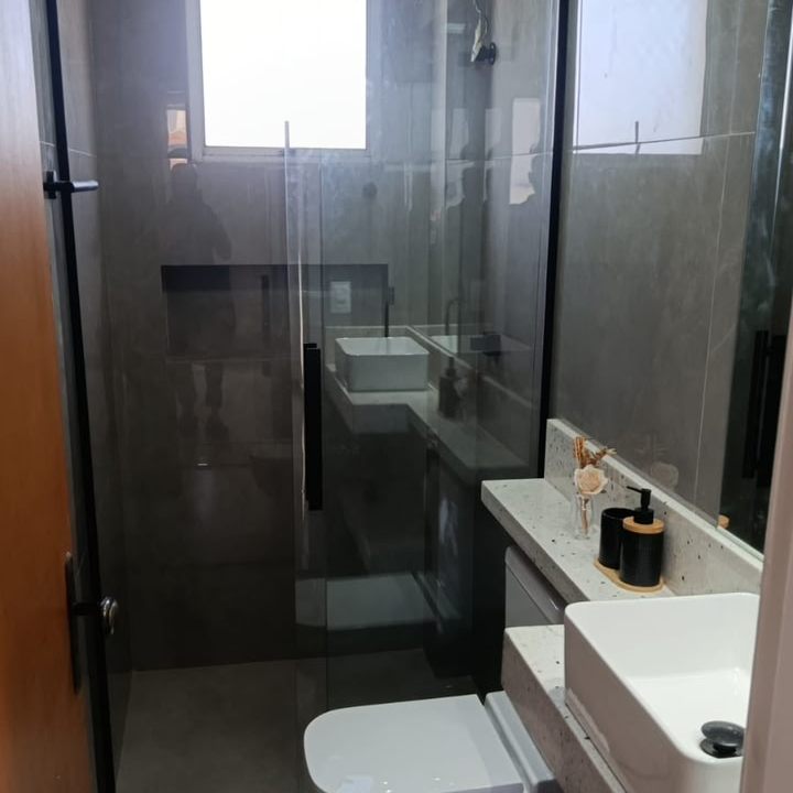 Banheiro com box de vidro em perfil preto e porcelanato cinza